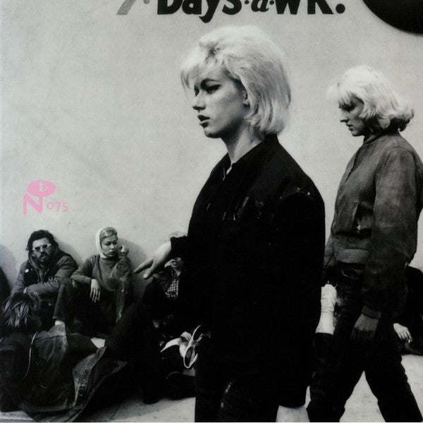 Black and white film still of a woman walking with others nearby.