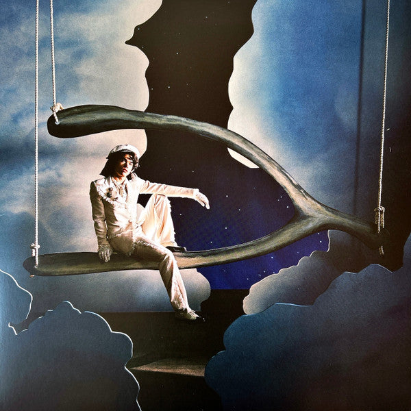Man in white suit sits on a large wishbone swing in clouds.