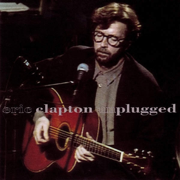 Eric Clapton with guitar and microphone, album cover image.