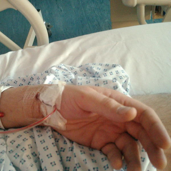 Hand with an IV drip connected to a clear plastic tube.