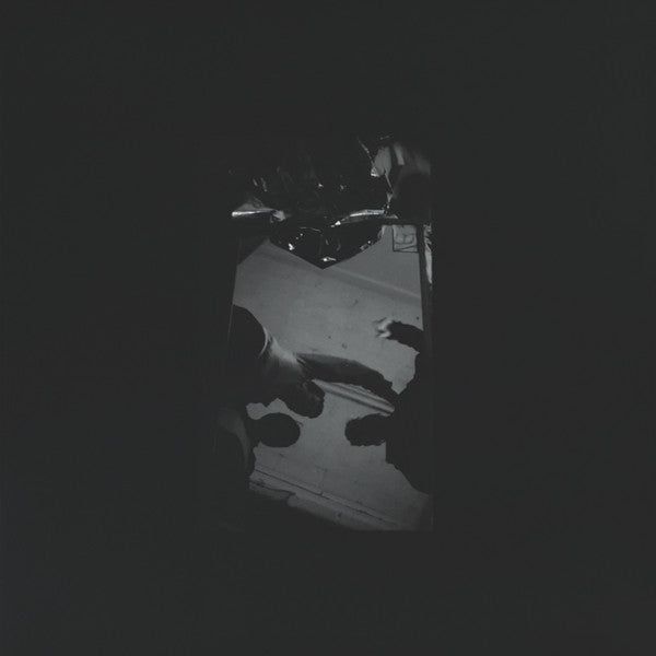 Dark, abstract image of feet and a reflective surface.