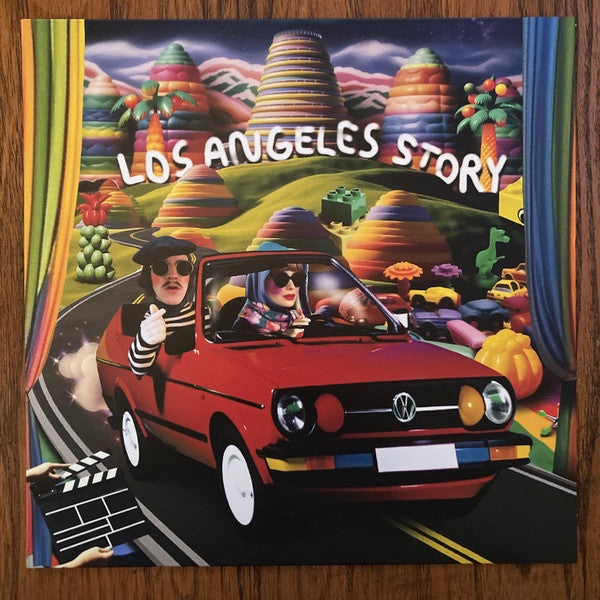 Album cover: red car with two people driving through a colorful landscape.