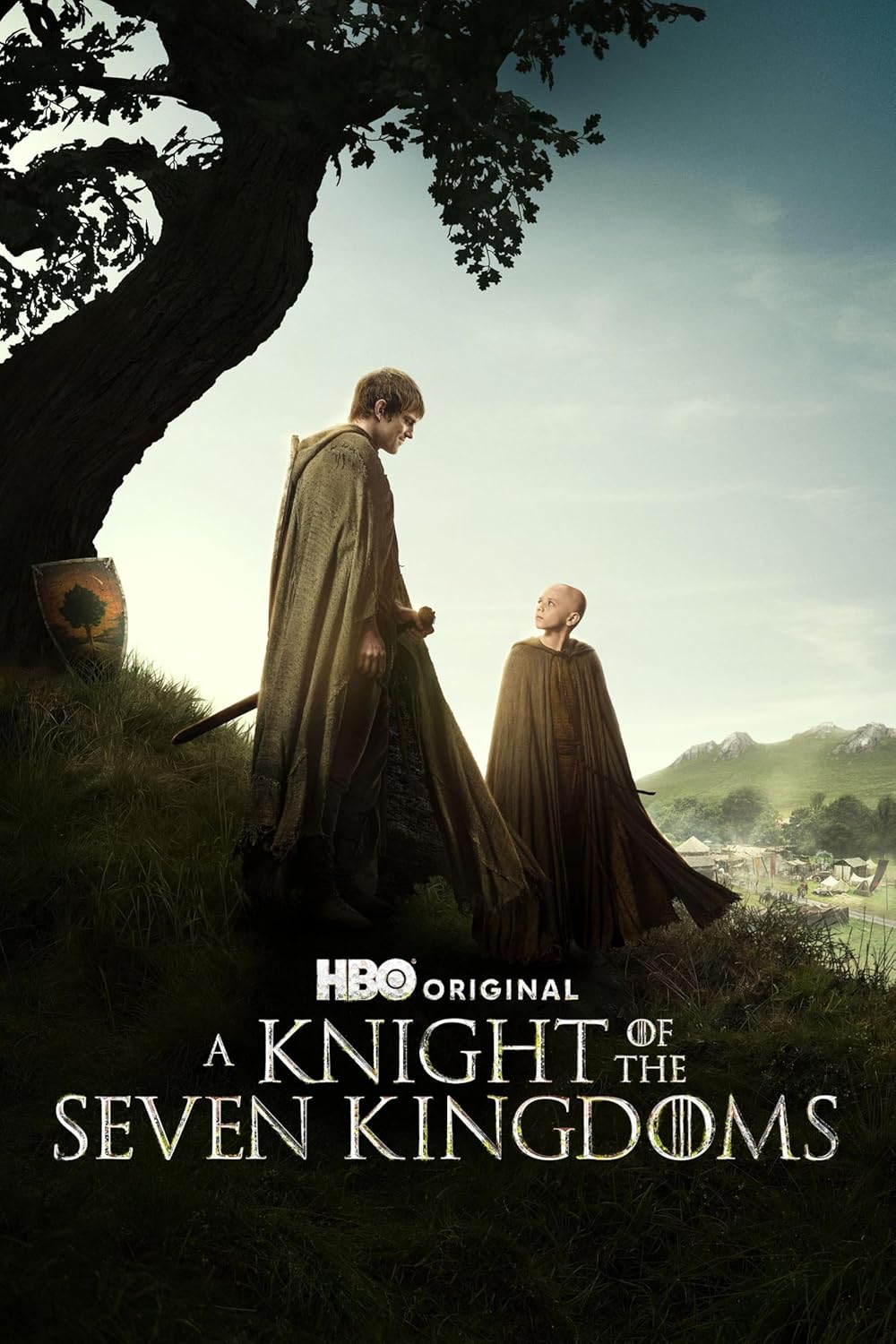 Two figures in cloaks walk through a field toward a distant village.