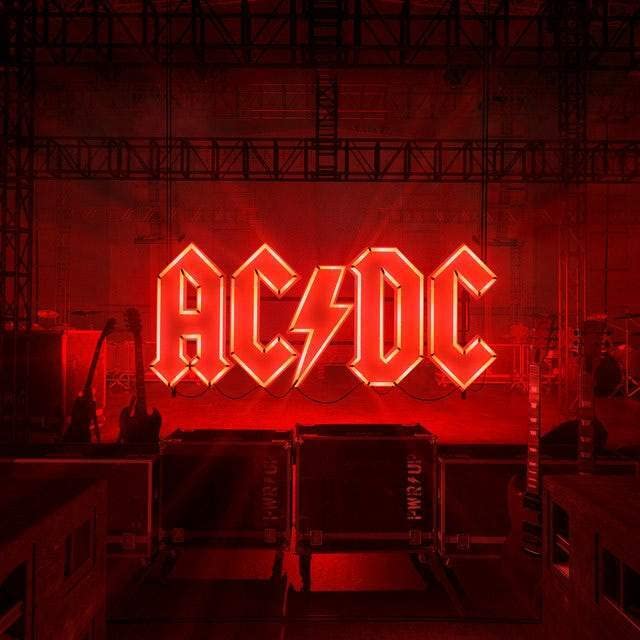 AC/DC logo in red neon lights against a blurred red stage backdrop.