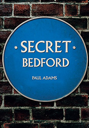 Blue plaque reading "Secret Bedford" by Paul Adams against brick wall.