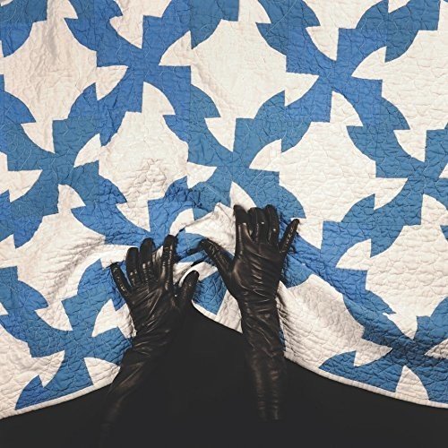 A vinyl record sleeve with a blue and white quilt pattern and black gloved hands.