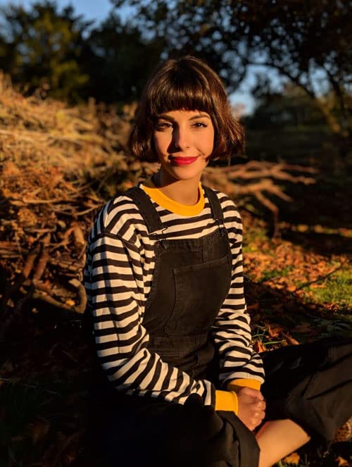 Young woman with short brown hair wearing striped shirt and overalls.
