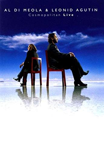 Two men sit on red chairs against a blue sky with reflections below.