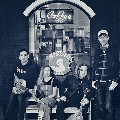 Four musicians with guitars pose in front of a coffee shop window.