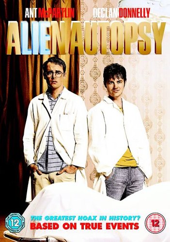 Two men in white lab coats stand beside a covered body on a table.