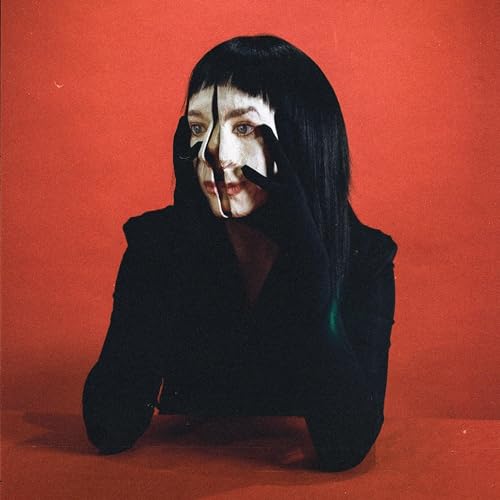 Close-up of Allie X with dark hair and bold white face paint on red.