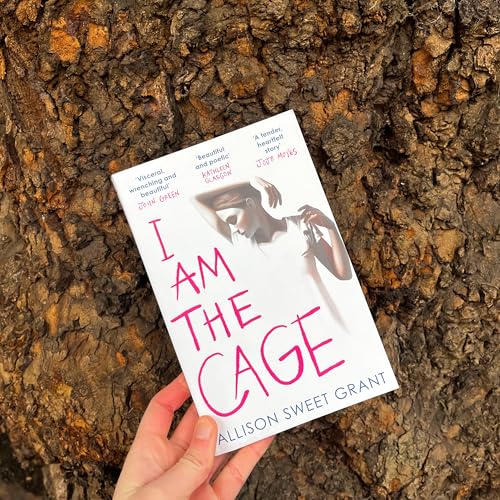 Book cover with a woman’s face, titled “I Am The Cage,” held in a hand.