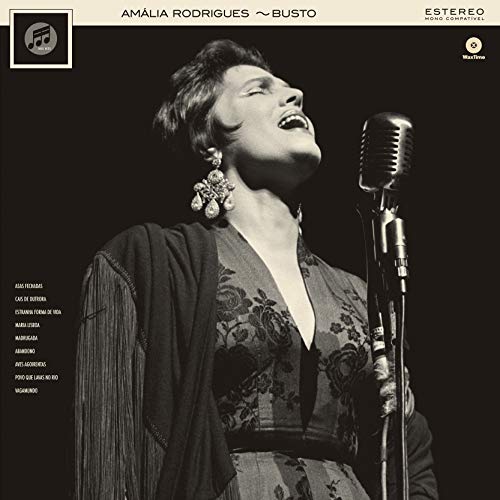 Black and white portrait of Amalia Rodrigues singing into a vintage microphone.