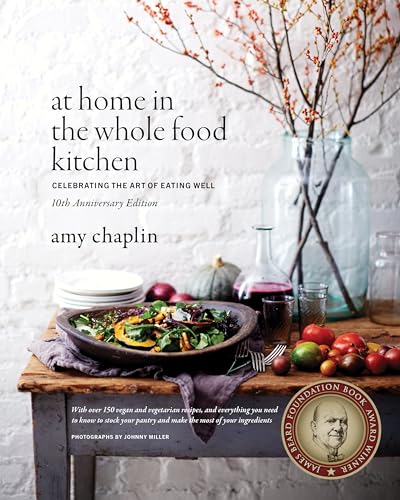 Cookbook "At Home in the Whole Food Kitchen" with autumnal produce and glassware.
