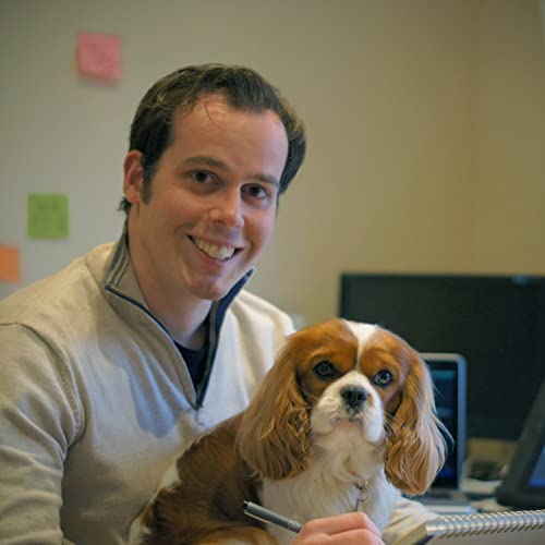 Man smiling with a Cavalier King Charles Spaniel in his arms.