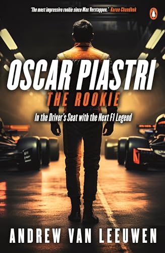 A race car driver stands facing away in a garage between two Formula One cars.