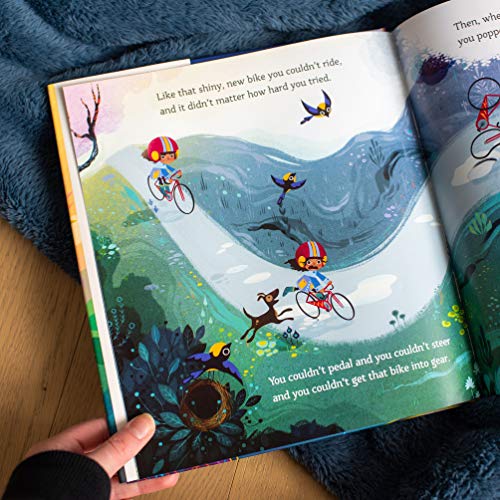 An open children's book shows illustrations of a child learning to ride a bike.