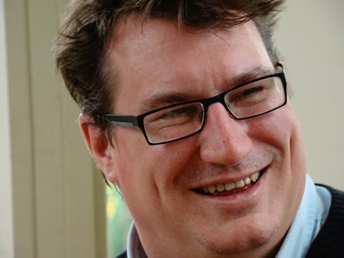 Close-up of a smiling man with short brown hair and glasses.