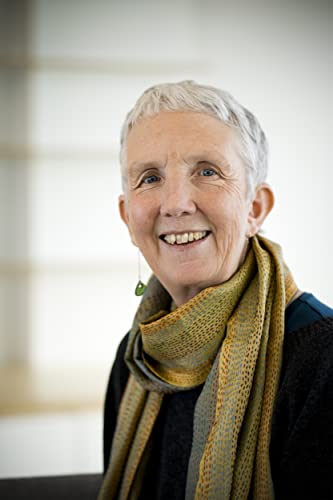 Smiling older woman with short white hair and a patterned scarf.