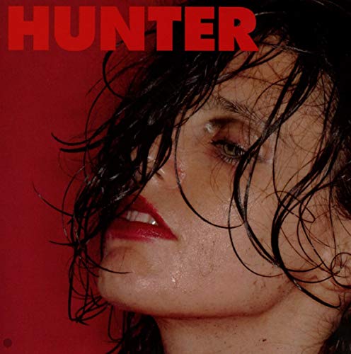 Close-up of Anna Calvi with wet hair against a red background.