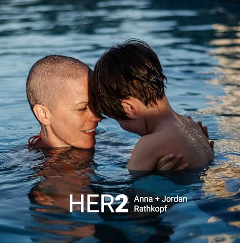 Woman with shaved head and child embrace in blue water.