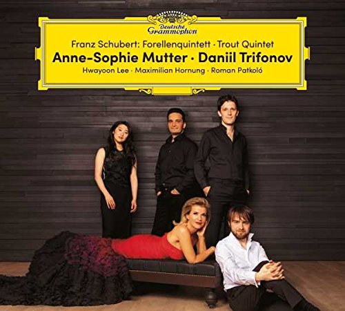 Five musicians posing in front of a dark wooden wall under a yellow label.