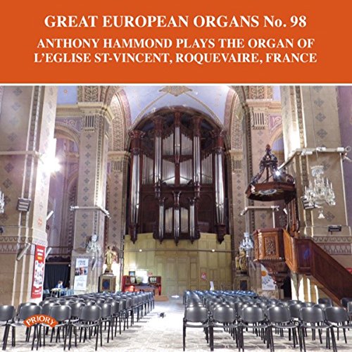 Large pipe organ inside a European church with rows of chairs.