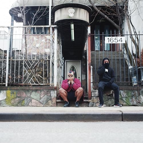 Two men in hoodies sit on steps in front of a house.