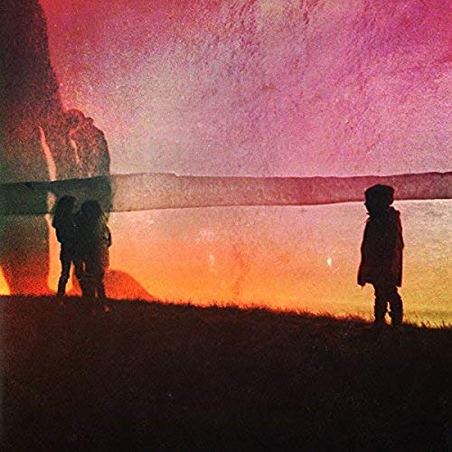 Silhouetted figures stand on a grassy hill against a vibrant pink and orange sunset.
