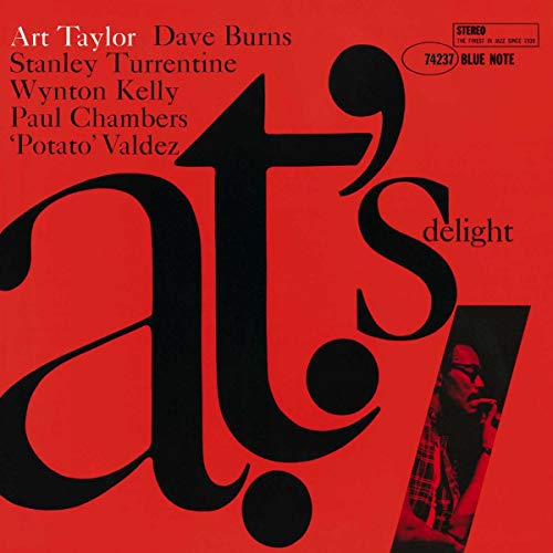 Red album cover with bold black text and a portrait in the corner.