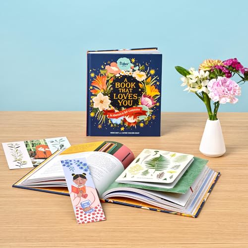 Open book with floral cover, bookmark, and small cards on a table.