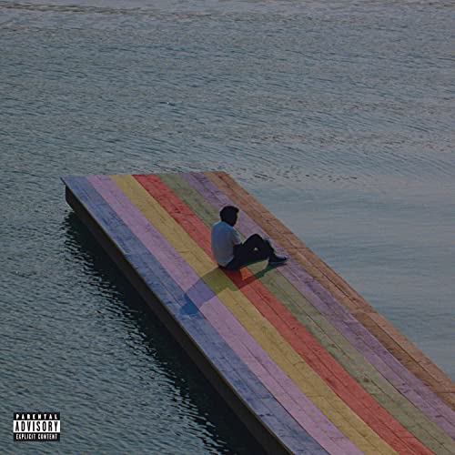 A person sits on a multicolored wooden dock extending into calm water.