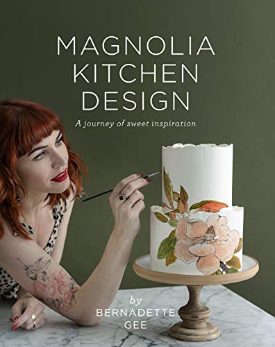 Woman with red hair painting floral designs on a whiteLCtwo-tier white cake.