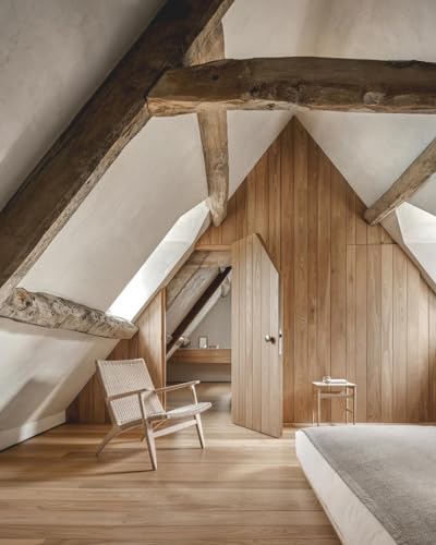 Attic bedroom with wooden beams, light walls, and minimalist furniture.