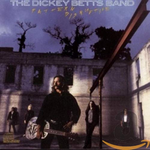 The Dickey Betts Band stands in front of a ruined building at twilight.