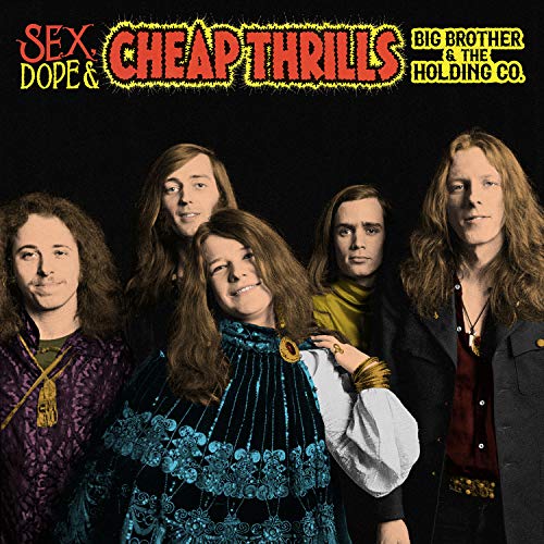 Five band members in 1960s clothing pose together on a dark background.