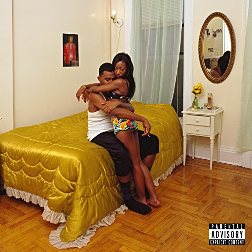 Couple embracing on a yellow bed in a room with a mirror.
