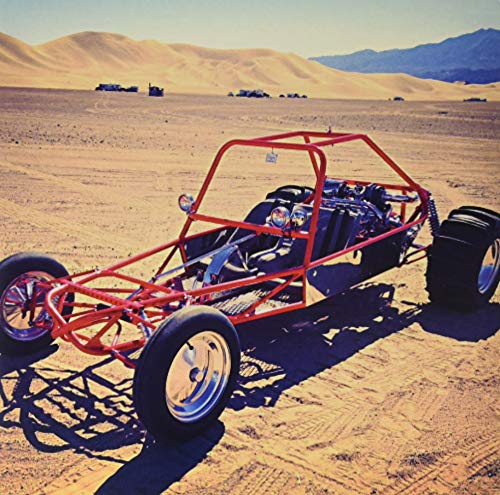 Red dune buggy parked on a sandy desert landscape.