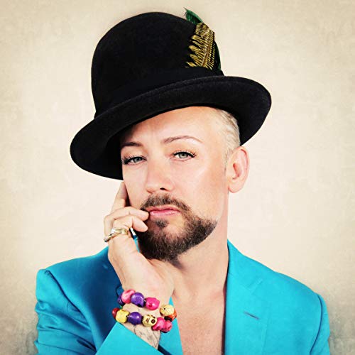 Boy George wearing a black hat with a feather and a bright blue jacket.