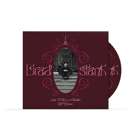 CD cover with a maroon background, ornate pink frame, and a central black-and-white photo.