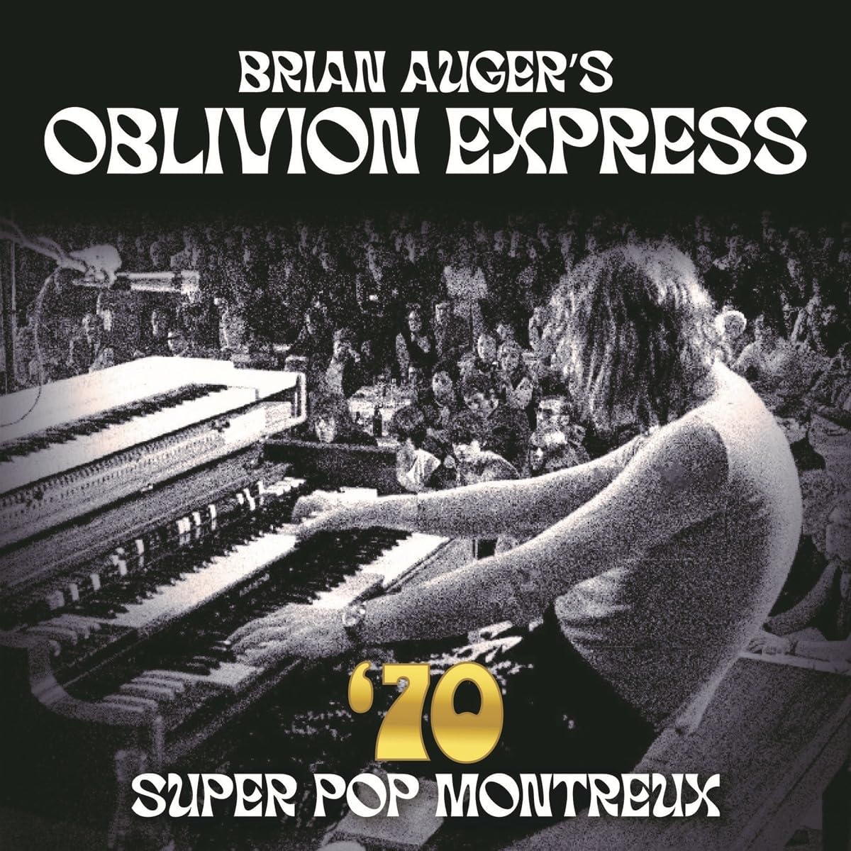 Black and white photo of Brian Auger playing keyboards before a live audience.