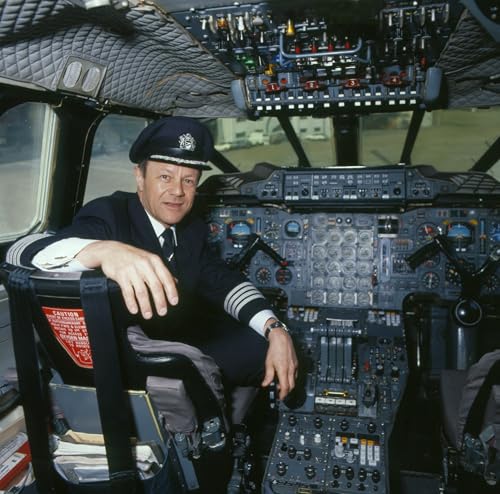 Pilot in uniform seated in the cockpit of a Concorde airplane.