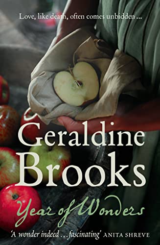 A person holds a sliced apple in a cloth, with red apples nearby.