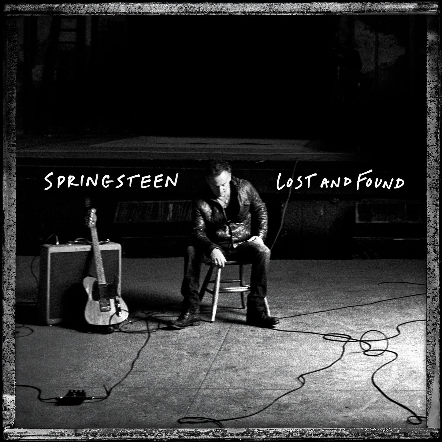 Black and white album cover featuring Bruce Springsteen sitting with a guitar.