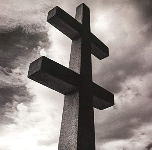 Black and white image of a stone cross against a cloudy sky.