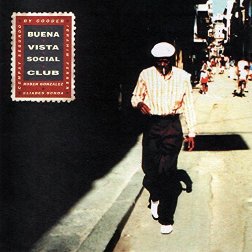 "Album cover with man walking down a street, vintage car, and cityscape."