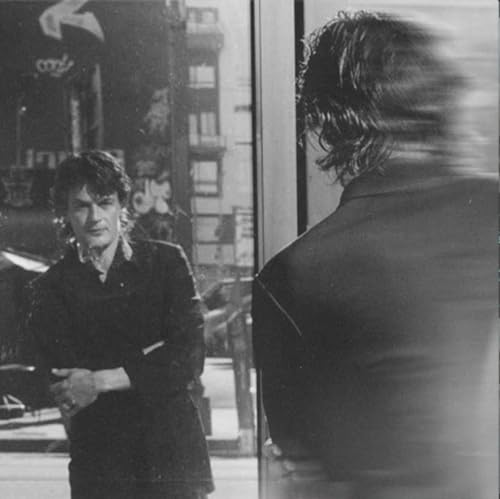 Black and white photo of a man reflected in a window, with motion blur.