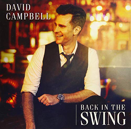 David Campbell wearing a vest and tie against a blurred, warm-toned bar background.