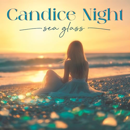 A woman in a white dress sits on a beach at sunset with sea glass.