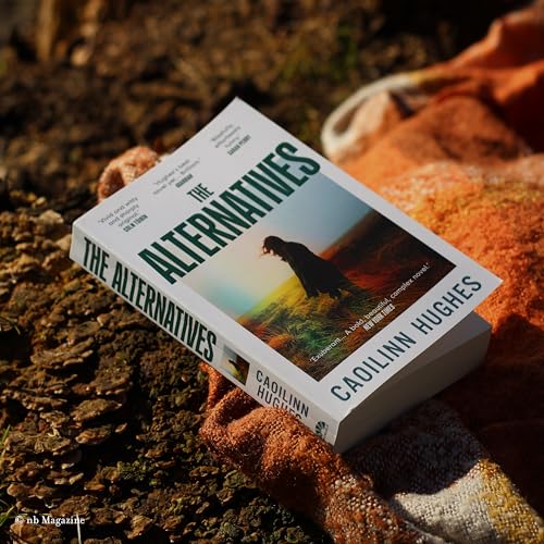 The book The Alternatives by Caoilinn Hughes resting on a textured orange blanket outdoors.